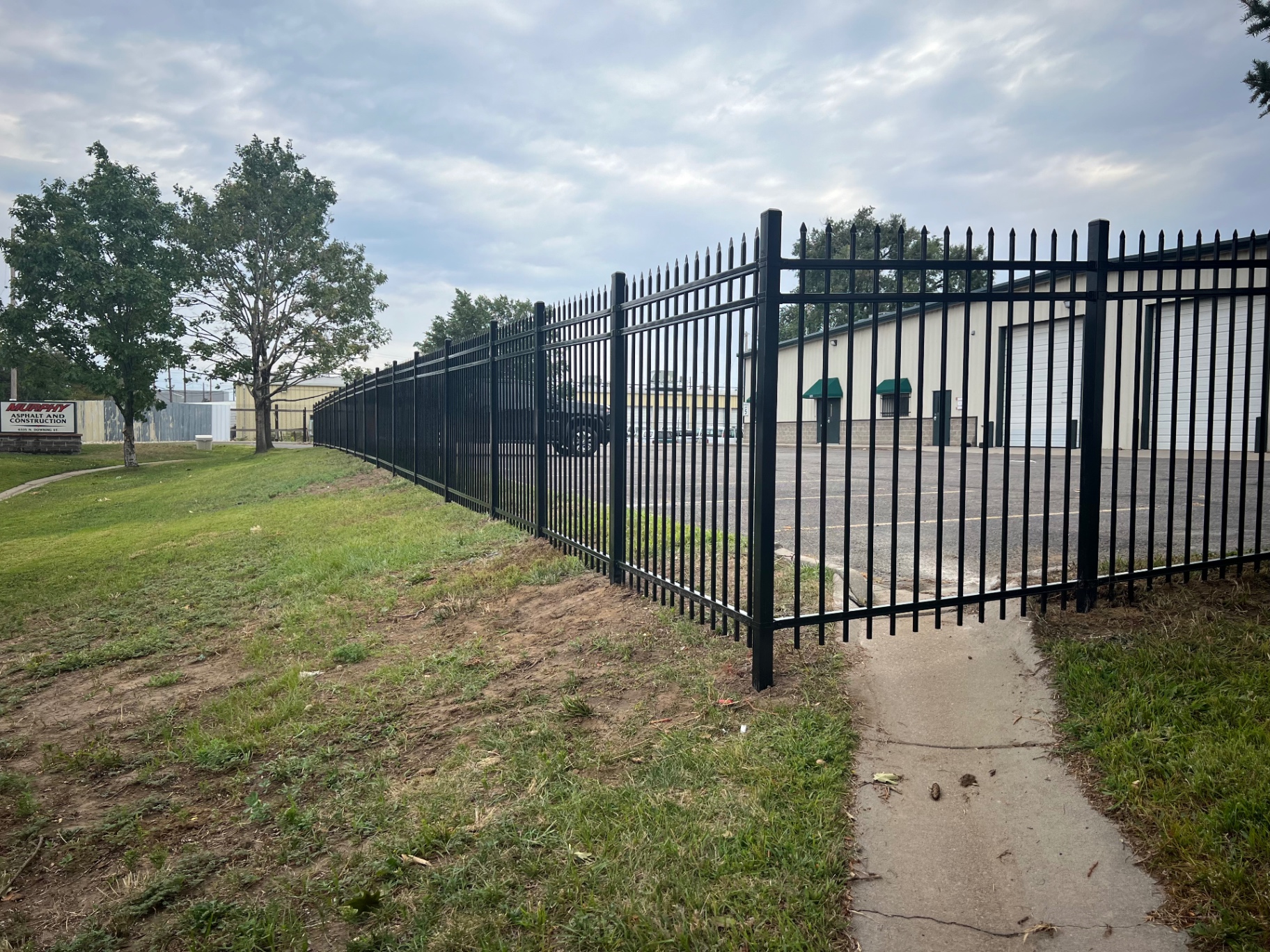 Tall spear top residential ornamental iron security fence enclosing a commercial property