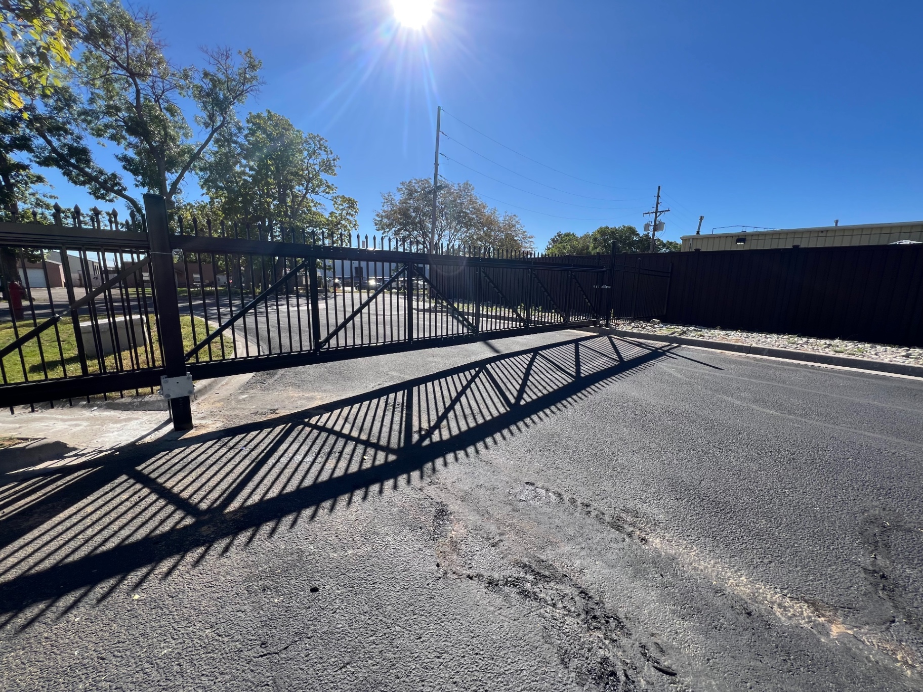 Wide black residential ornamental iron security driveway gate at a commercial property