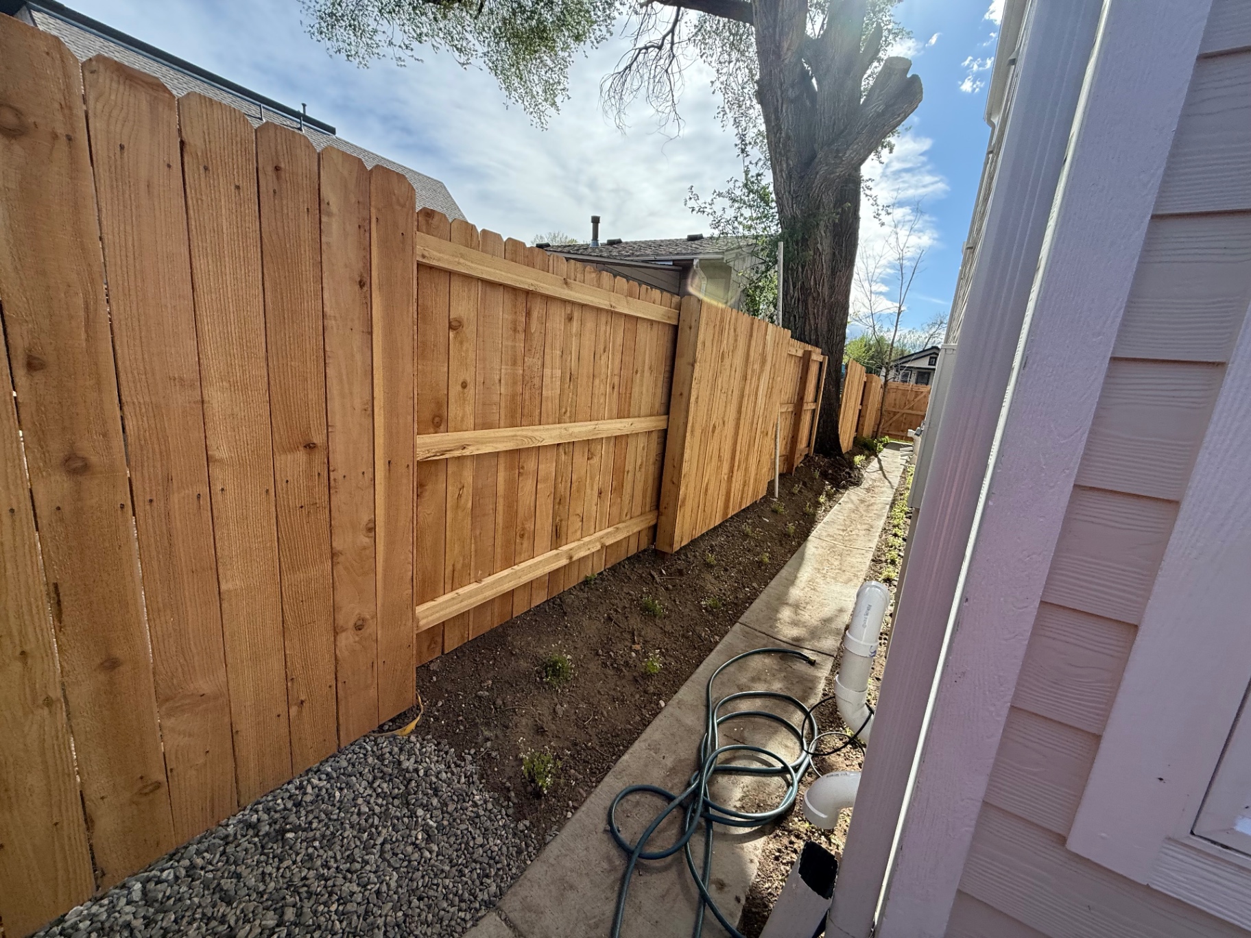 Dog ear cedar privacy fence installed along a residential side yard walkway