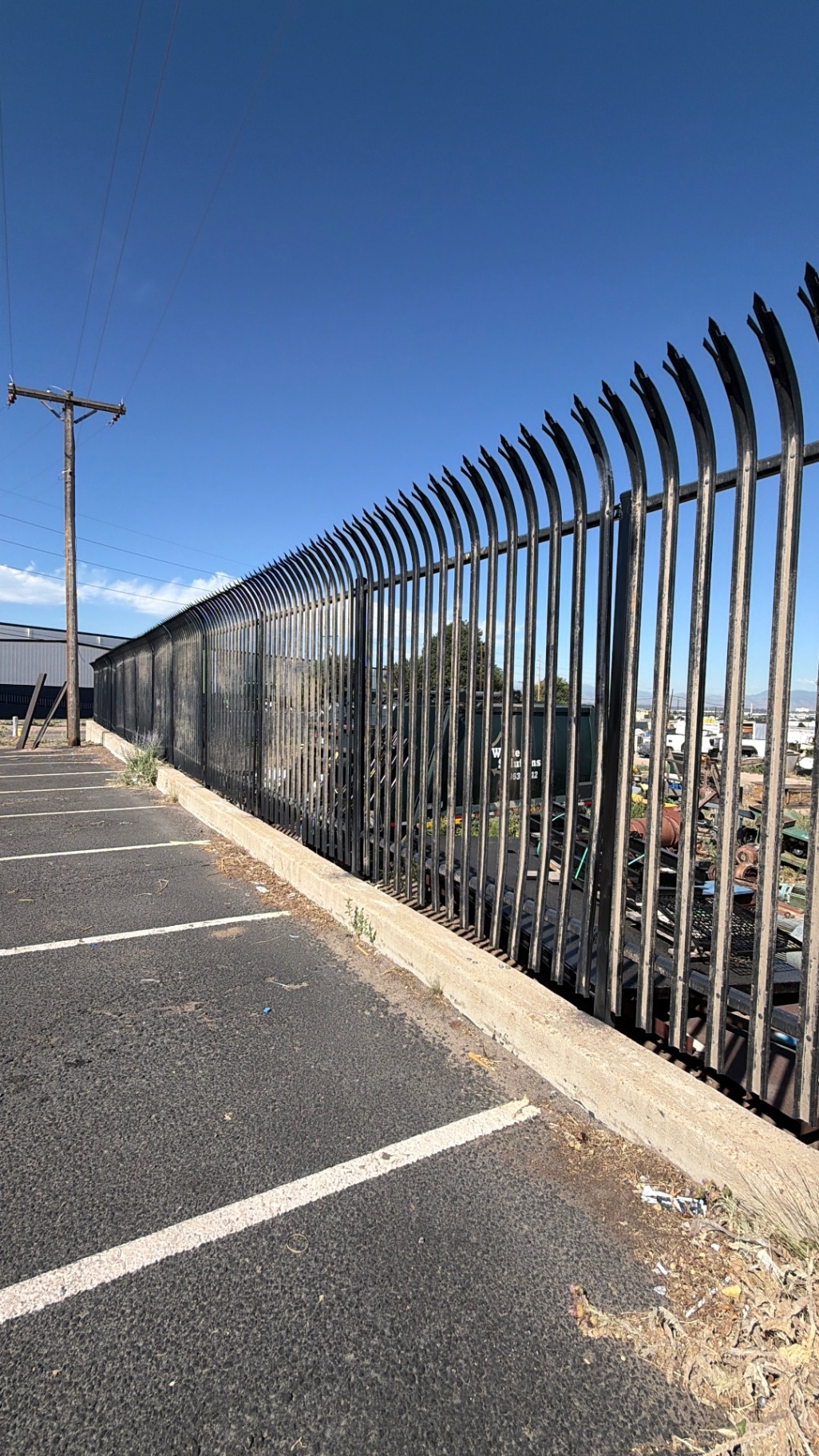 Tall black residential ornamental iron security fence installed along a Colorado property line